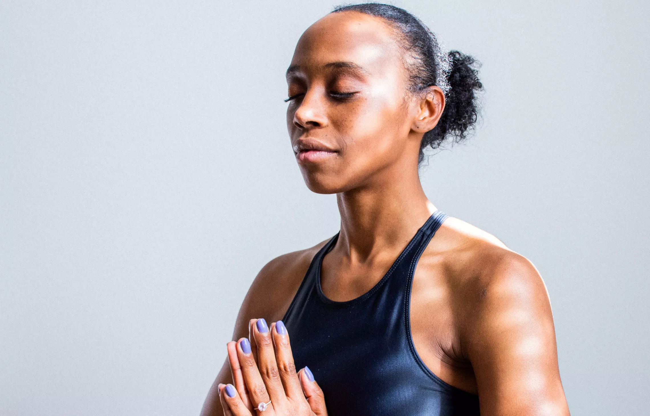 Sun-dappled black woman meditating with eyes closed