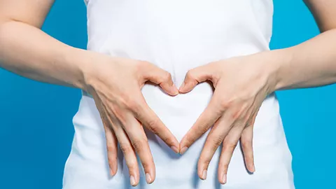 person making heart with hands over stomach